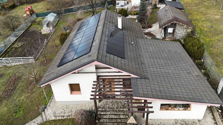 Rodinný dom so sivou strechou a čiernymi fotovoltickými panelmi